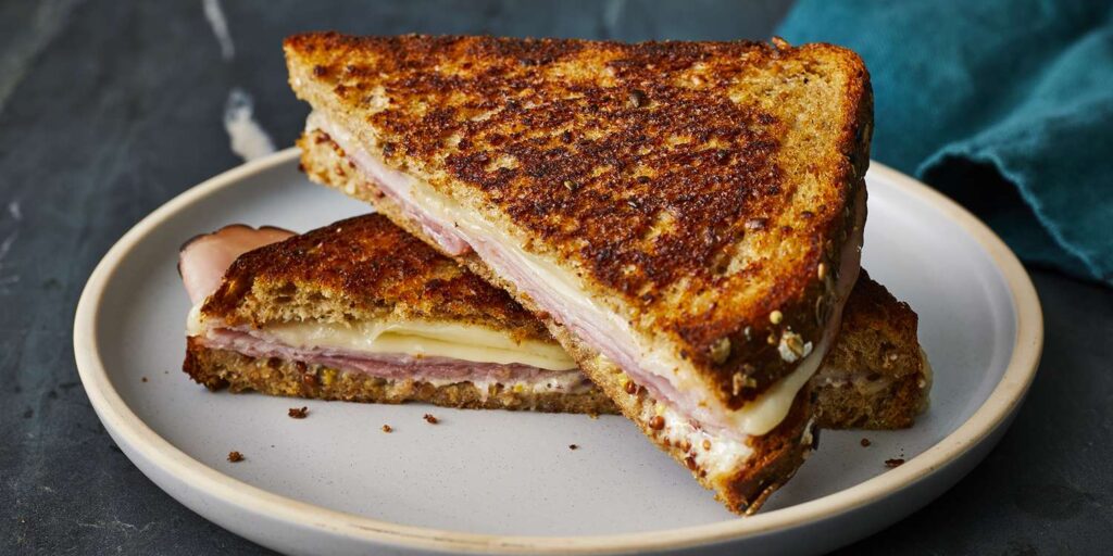 Grilled rye bread with swiss cheese, ham slices and fried onions